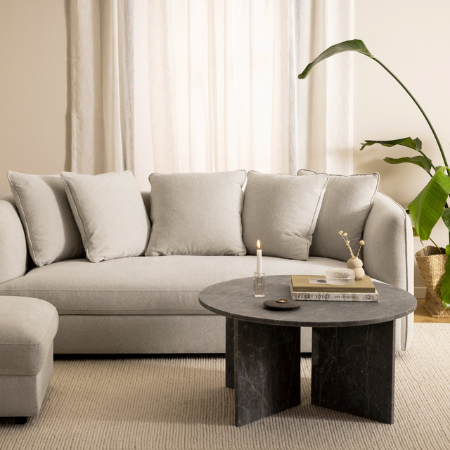 Neutral living room with beige sofa and round stone coffee table
