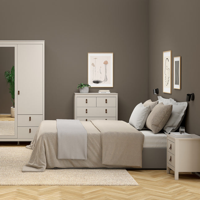 Bedside table with two drawers, featuring rounded handles, in a light wood finish, placed beside a bed in a neutral-toned