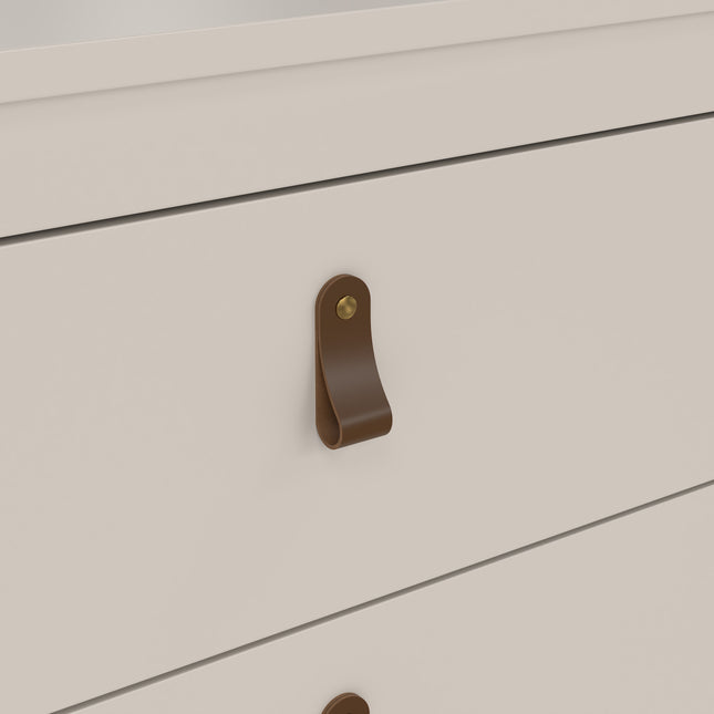 Close-up of a drawer handle featuring a brown leather strap with a brass button, set against a white cabinet surface
