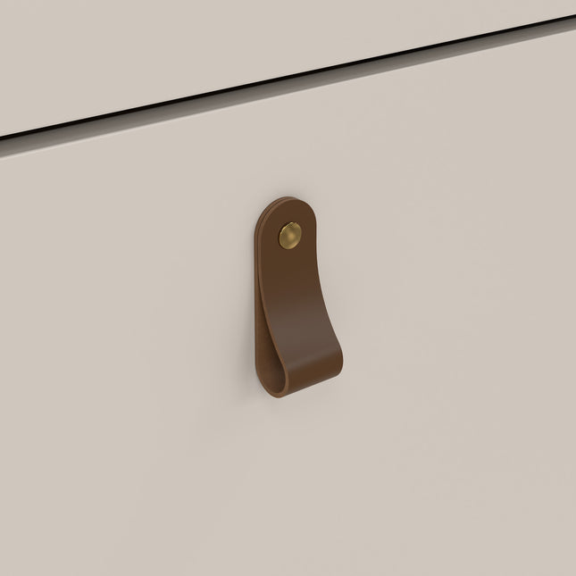Brown leather handle with a brass rivet on a smooth, light-coloured cabinet door