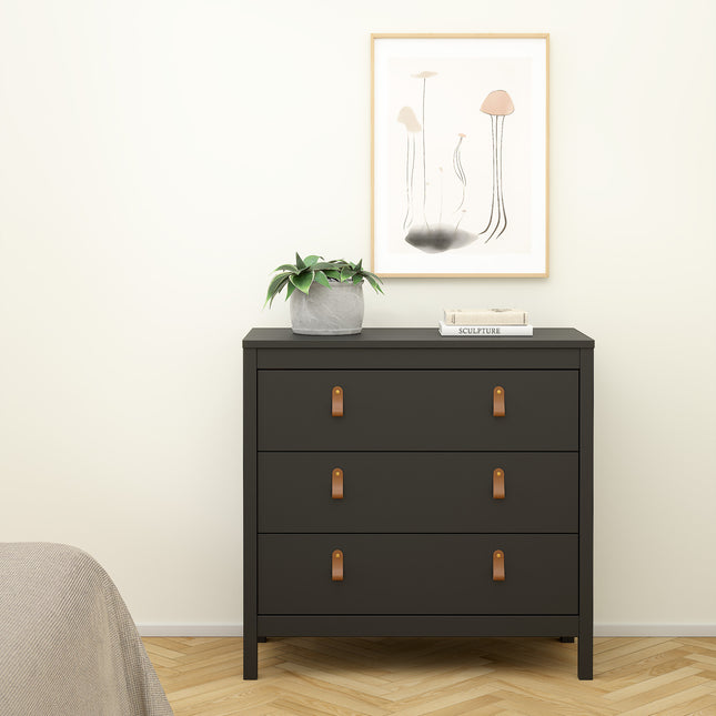 Three-drawer chest in dark grey with leather strap handles, topped with a potted plant and framed artwork