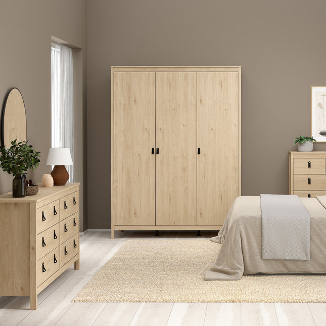 Double dresser with four large drawers, light wood finish, black handles, placed against a neutral wall