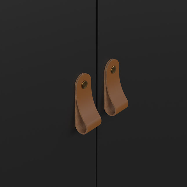 Close-up of two brown leather handles on a black cabinet door, featuring a simple loop design and metal fasteners