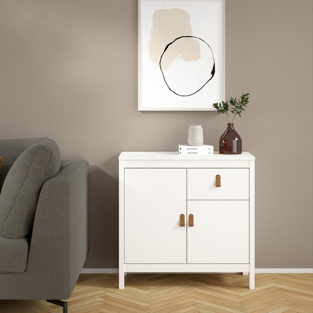 White sideboard with two doors and one drawer, featuring brown leather handles, set against a neutral wall
