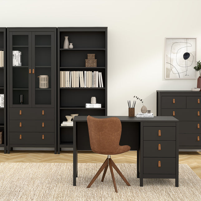 Desk with three drawers, a smooth black finish, paired with a brown upholstered chair on a light rug, surrounded by shelves