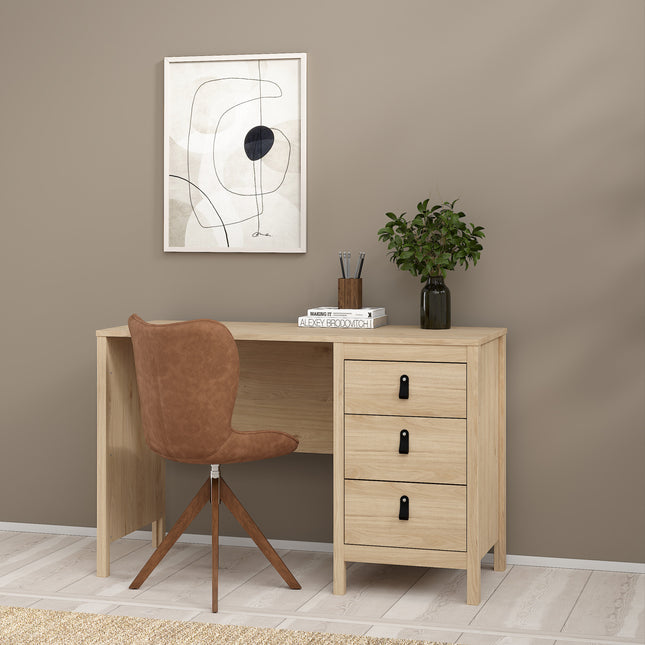 Desk with three drawers, light wood finish, accompanied by a brown upholstered chair and a potted plant