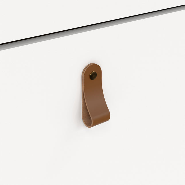 Brown leather handle on a white cabinet door, featuring a rounded loop design and a small metal stud
