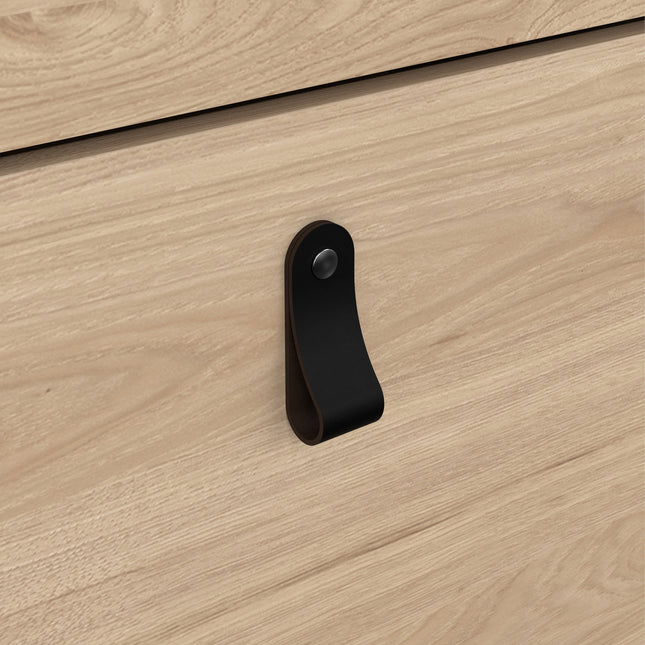 Close-up of a wooden cabinet door featuring a black leather handle with a metal stud, set against a light wood finish