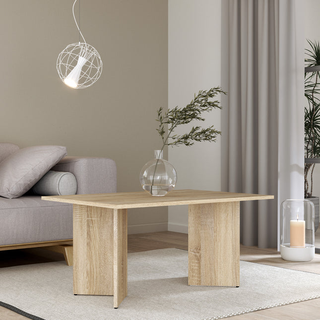 Square coffee table with a natural wood finish and a minimalist design, set on a light rug beside a grey sofa