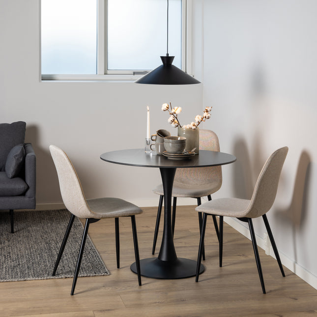 Round dining table with a black pedestal base, surrounded by two beige upholstered chairs with slender black legs