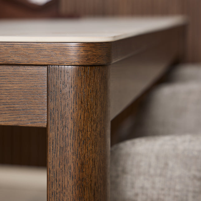 Rectangular dining table with a smooth cream ceramic top and a sturdy wooden frame in a rich brown finish