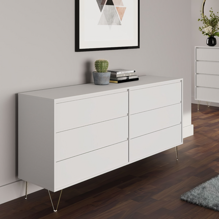 Six-drawer chest in white with sleek front panels and gold metal legs, set against a neutral wall and wooden floor