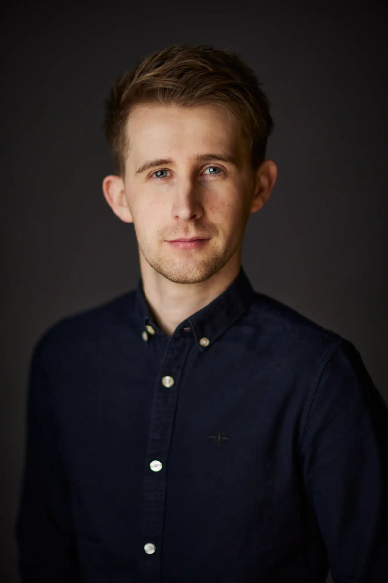Navy blue button-down shirt with white buttons and a small embroidered logo on the left chest
