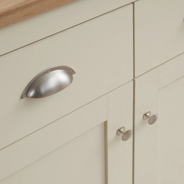 Close-up of pale cream sideboard door and drawer fronts with brushed metal cup handle and knob