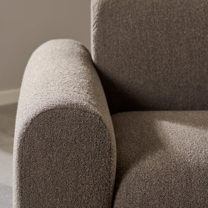 Close-up of taupe boucle upholstery on rounded arm and backrest