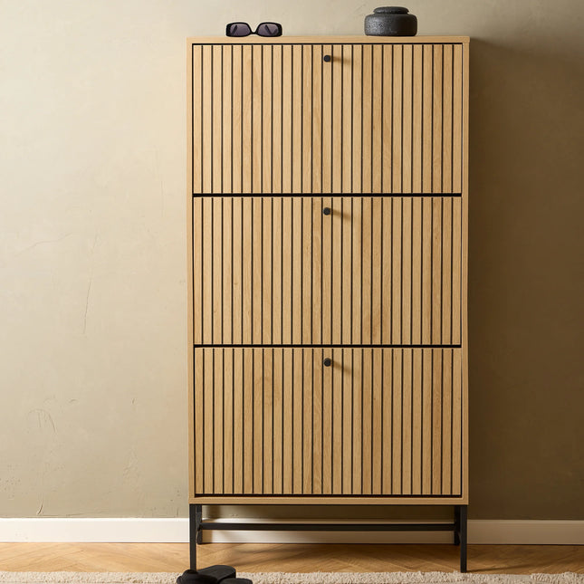 Close-up of oak-effect slatted shoe cabinet doors with black round knobs and metal base