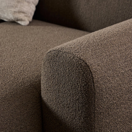 Close-up of brown boucle upholstery and rounded arm on chaise lounge