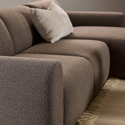 Close-up of brown boucle upholstery and rounded arm on chaise longue