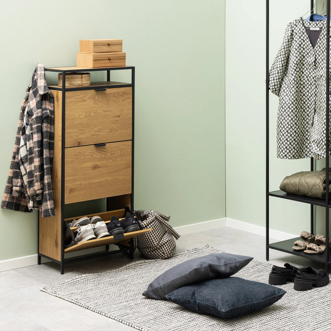 Open shoe compartment of Seaford shoe cabinet showing oak front, black metal frame and stored trainers